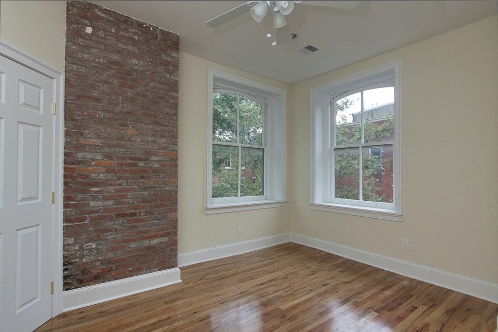 an empty living room with a brick wall and a wooden floor