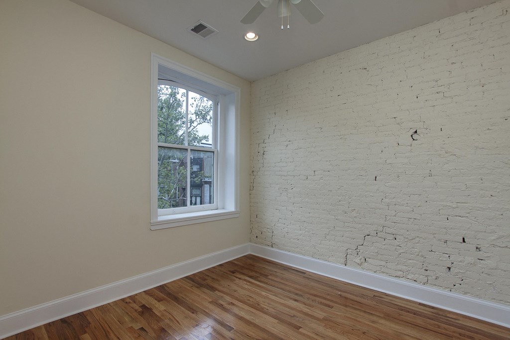 an empty room with a brick wall and a window
