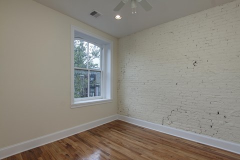 an empty room with a brick wall and a window