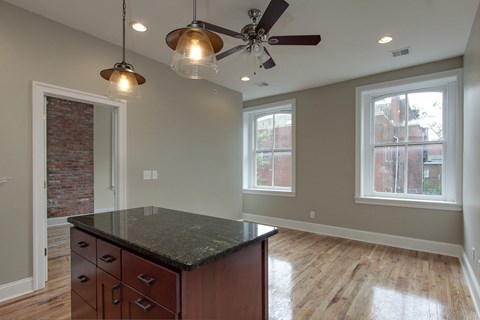 an empty kitchen with a island and a ceiling fan
