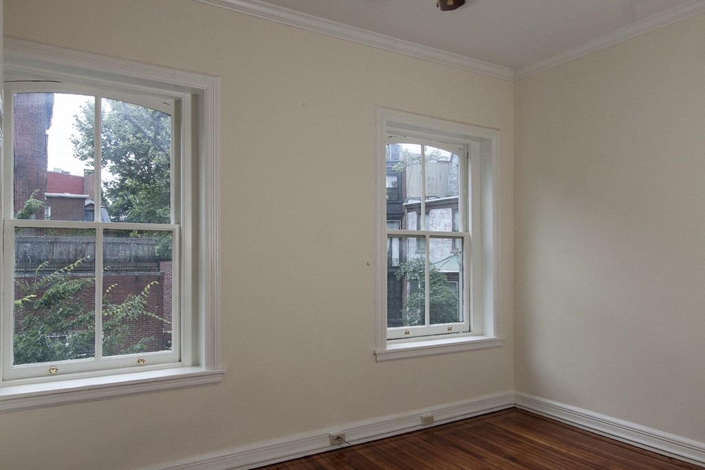 an empty room with two windows and a wooden floor