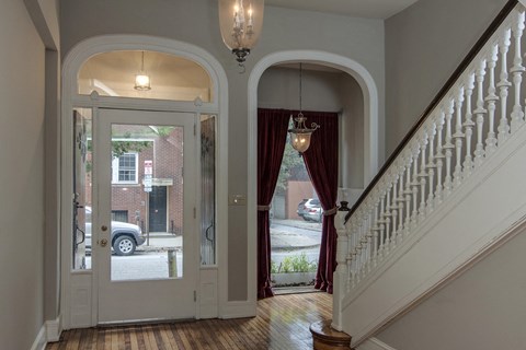 the entryway of a house with a staircase and a door to a street