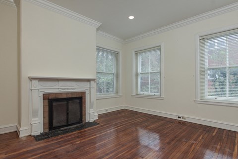 an empty living room with a fireplace and three windows
