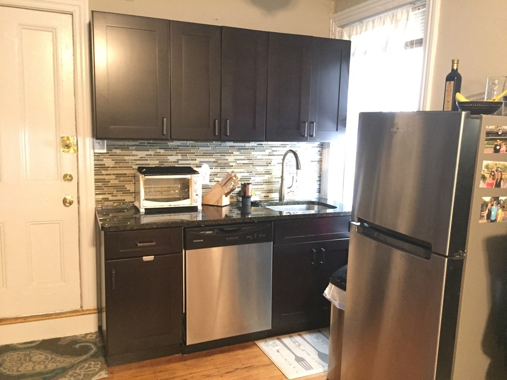 a small kitchen with stainless steel appliances and black cabinets