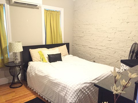 a bedroom with a bed and a white brick wall