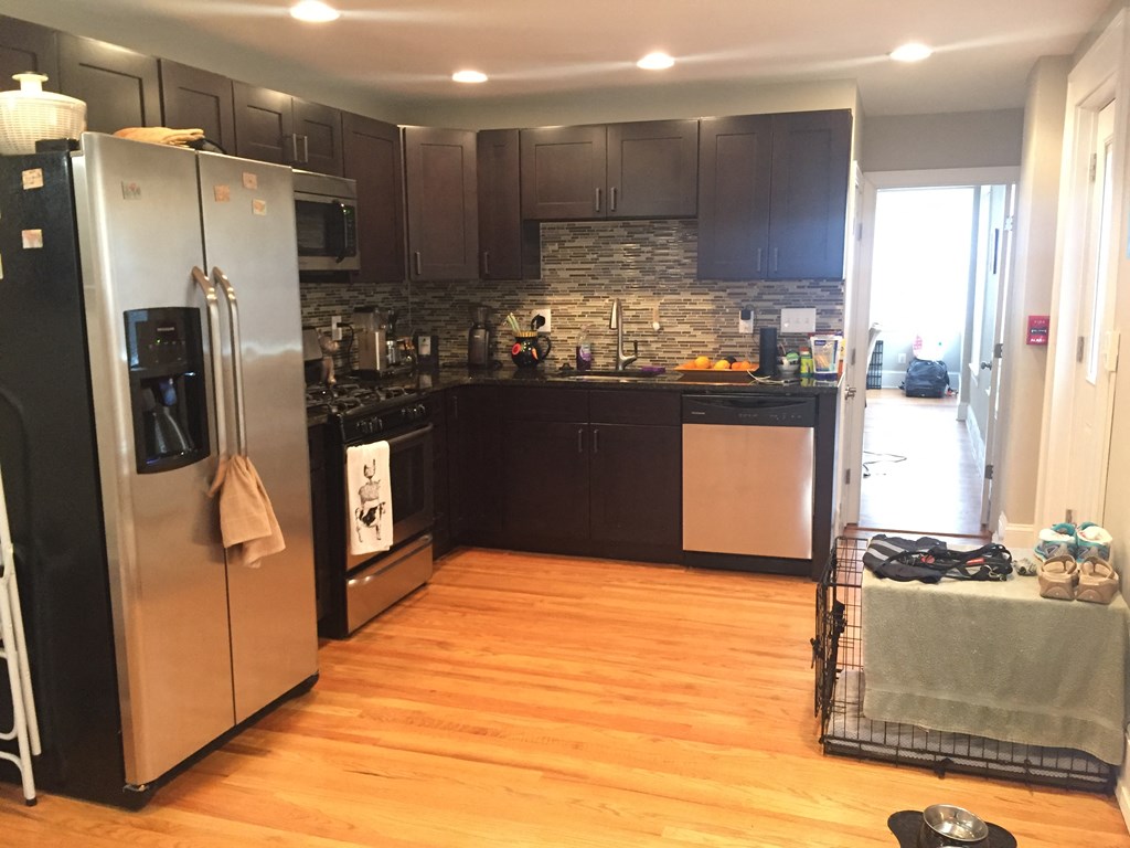 a kitchen with black cabinets and stainless steel appliances and a wooden floor