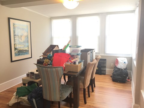 the dining room is cluttered with boxes and a table with chairs