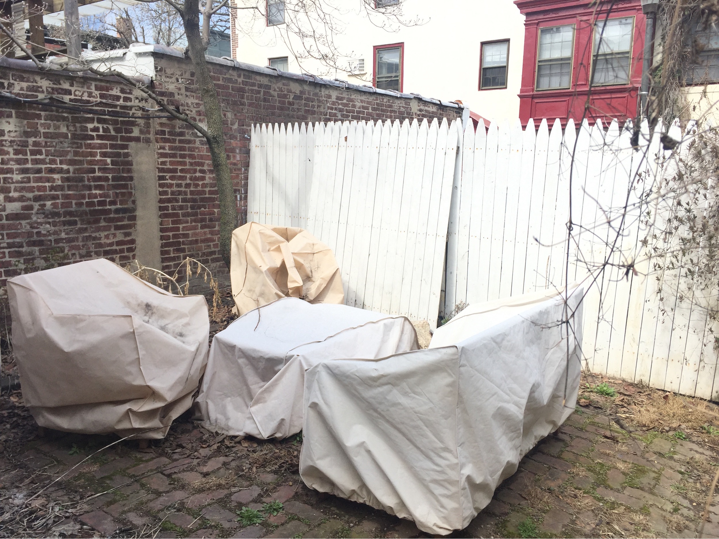 three covered trash cans in front of a white fence