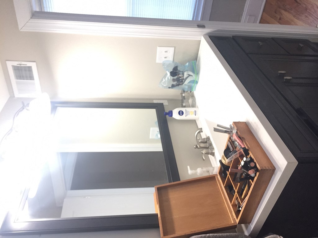 a view of the top of a bathroom vanity with a mirror and a wooden drawer