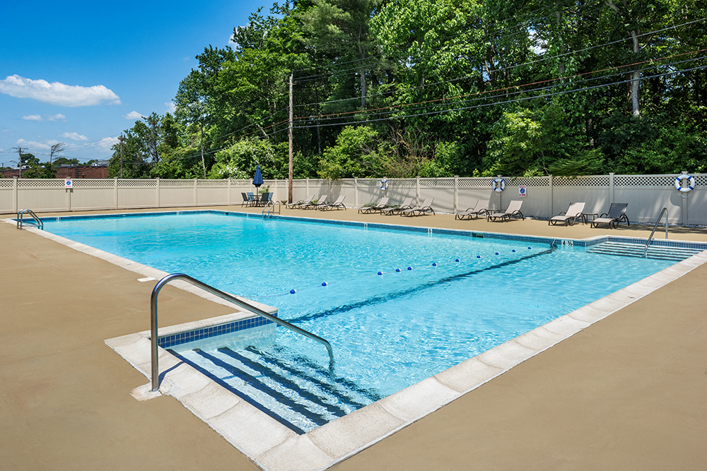 a swimming pool with chairs and a fence around it