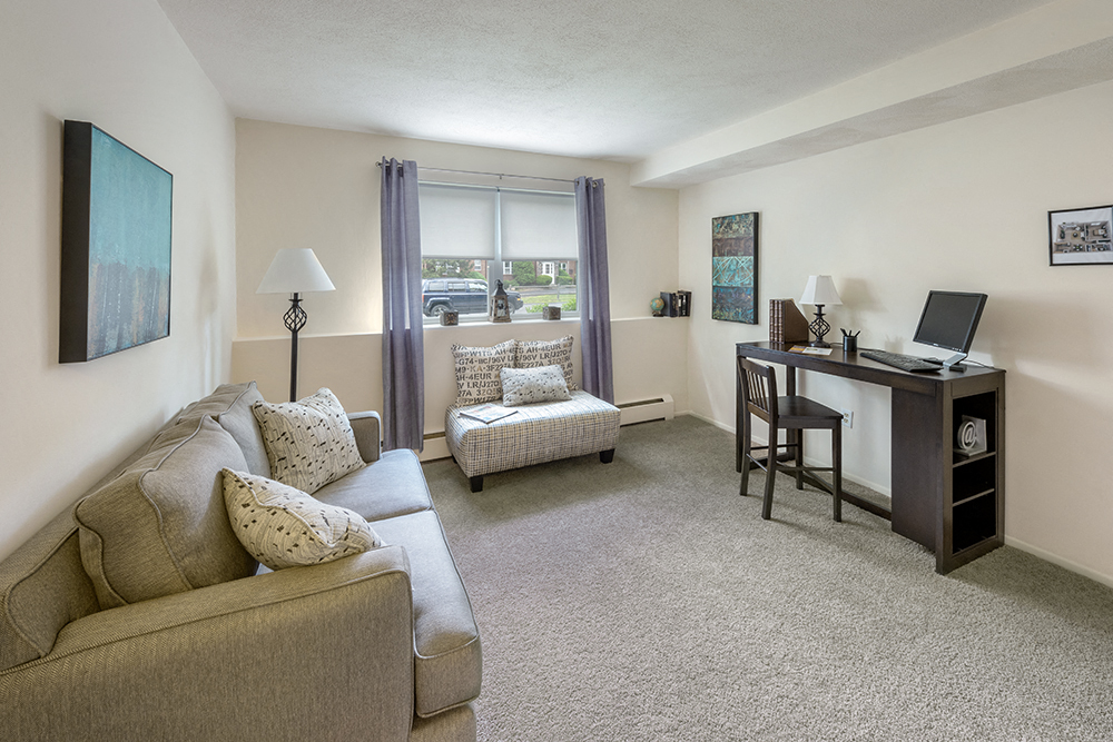 a living room with a couch and a desk and a window