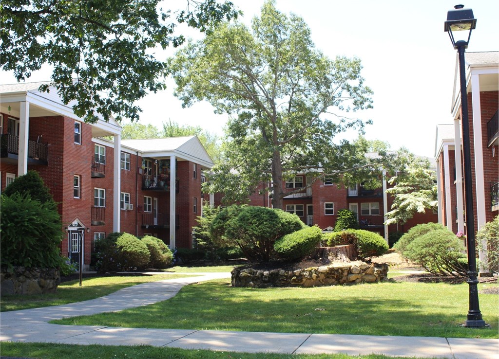 A street lamp stands on a sidewalk in front of a brick building.