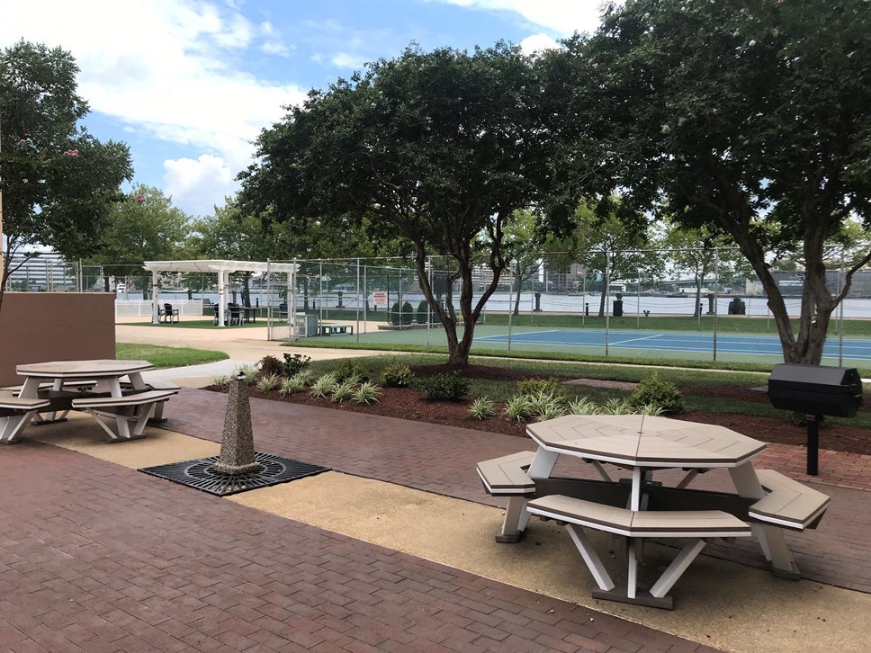 two picnic tables in a park next to a tennis court