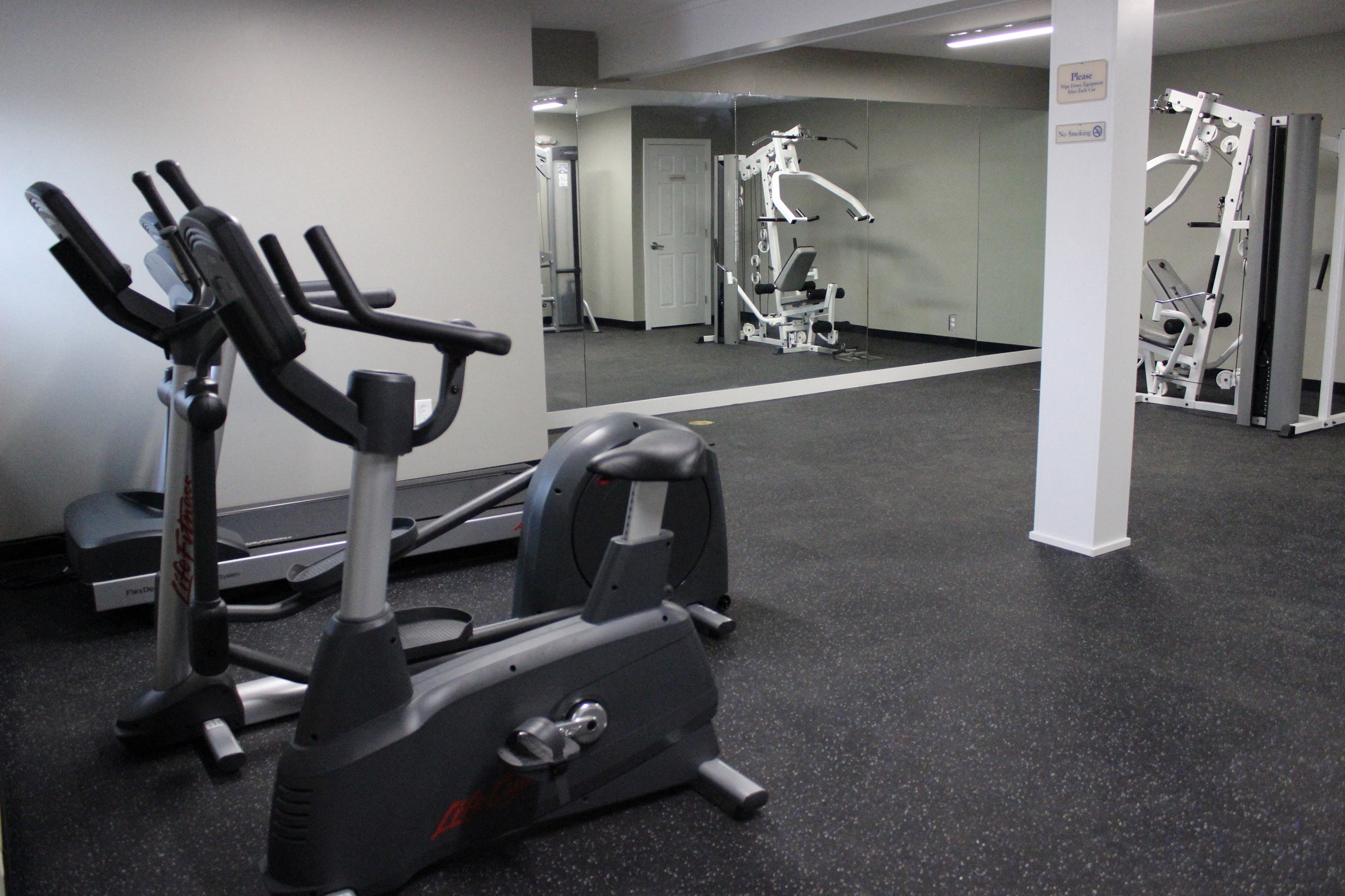 a gym with cardio equipment and weights on the floor