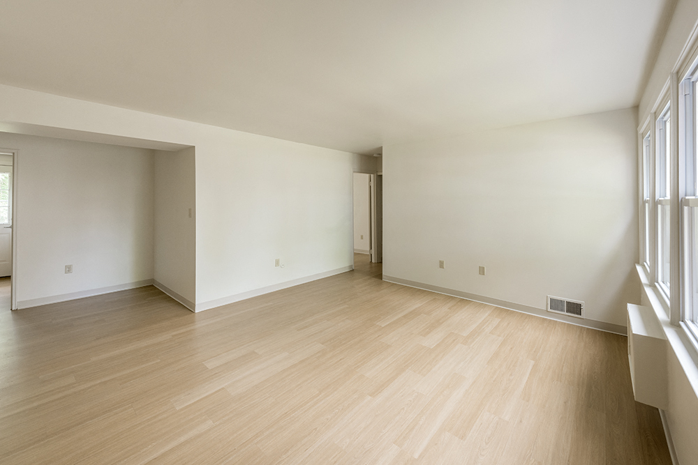 the living room and dining room of an empty house with wood floors and white walls