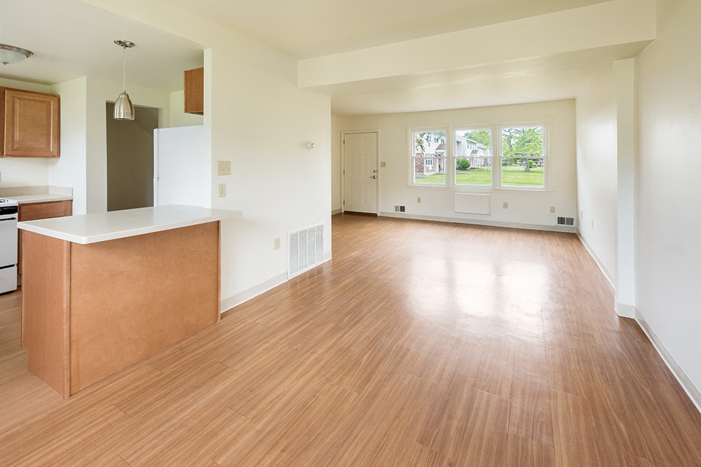 the living room and kitchen of an empty house with wood floors