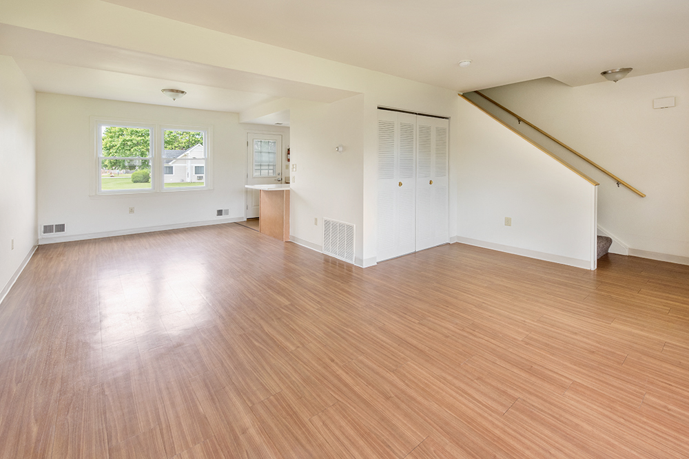 an empty living room with a hardwood floor and white walls
