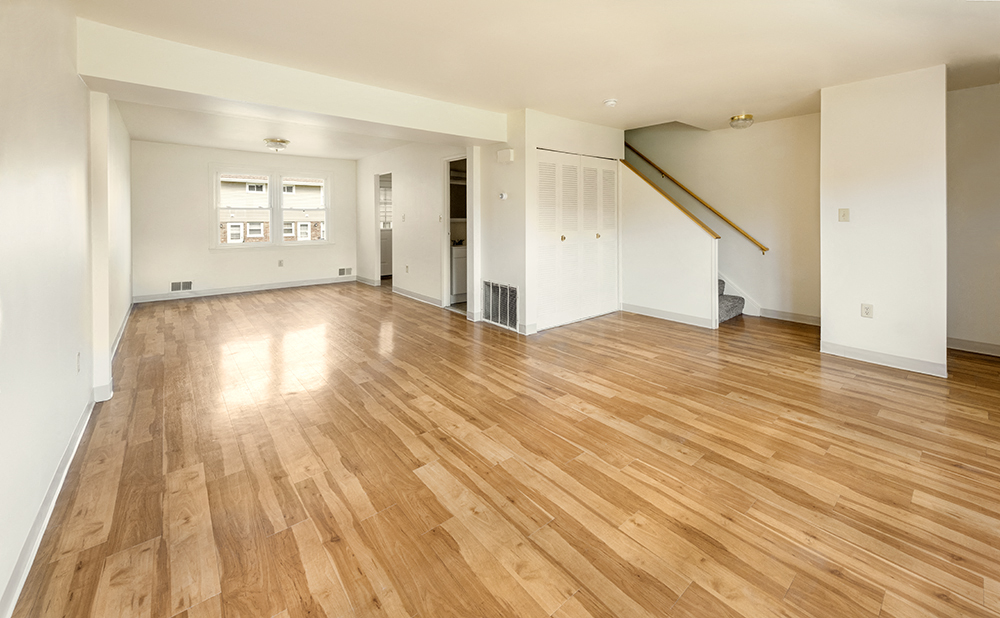 the living room and dining room of an empty house with wood flooring