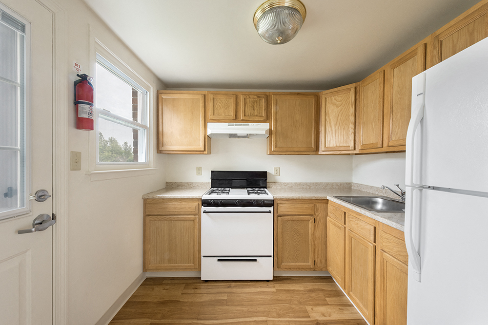 an empty kitchen with wooden cabinets and white appliances