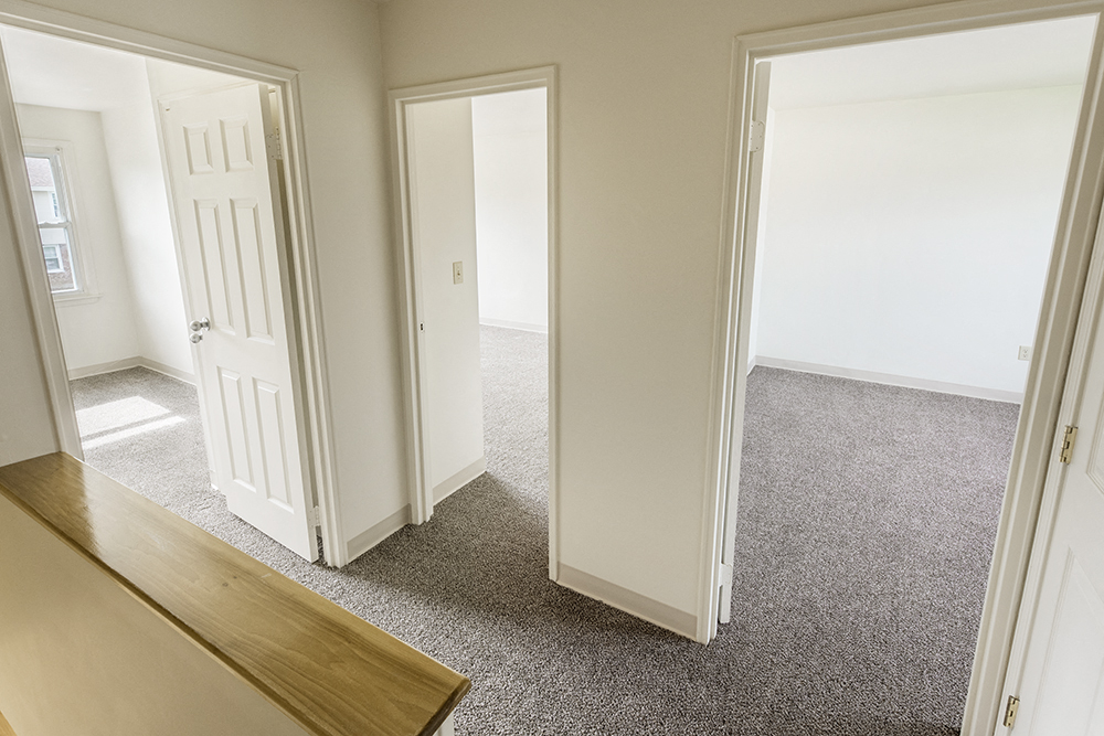 an empty living room with two doors and a carpeted floor
