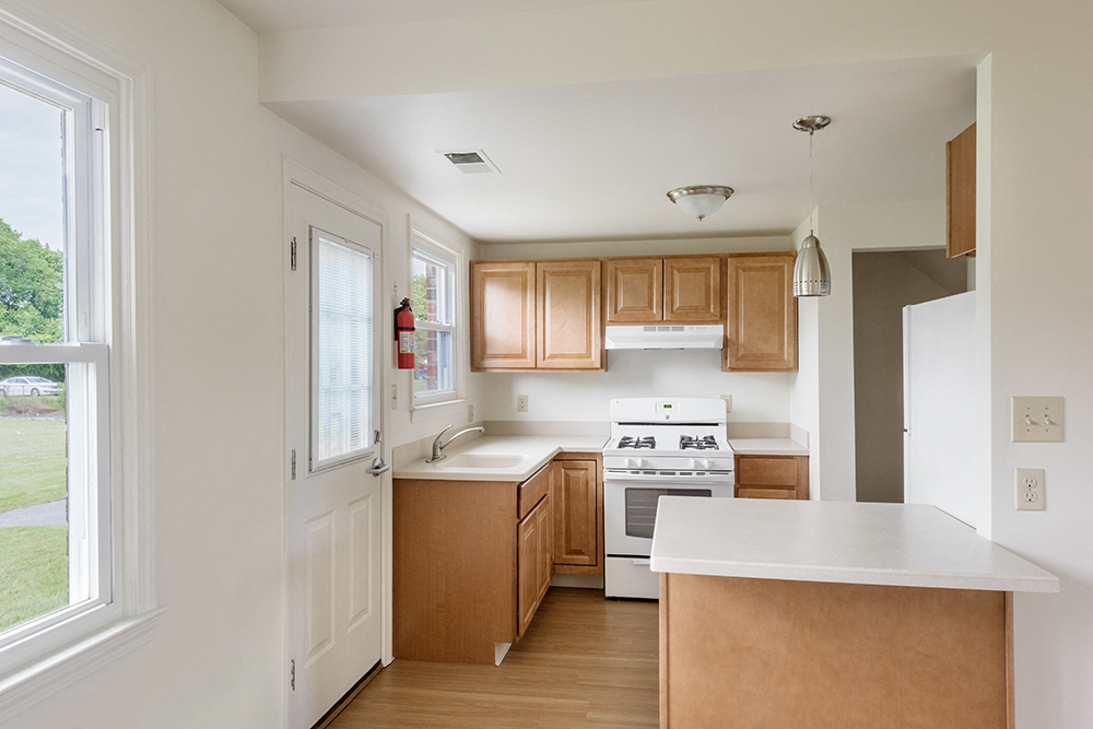 a kitchen with wooden cabinets and white countertops and a window