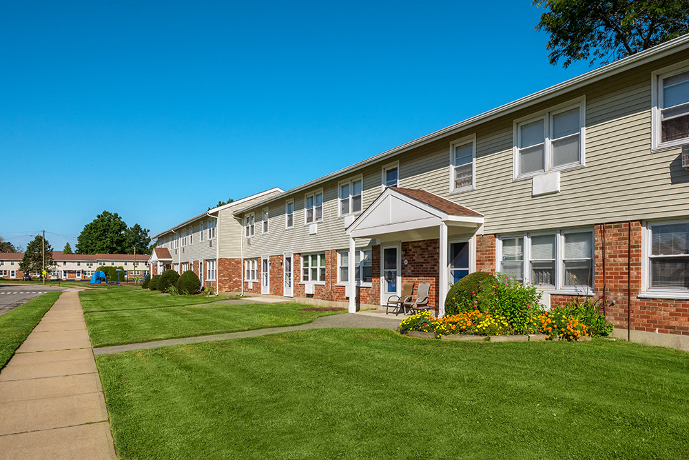 a row of town homes with a green lawn and a sidewalk