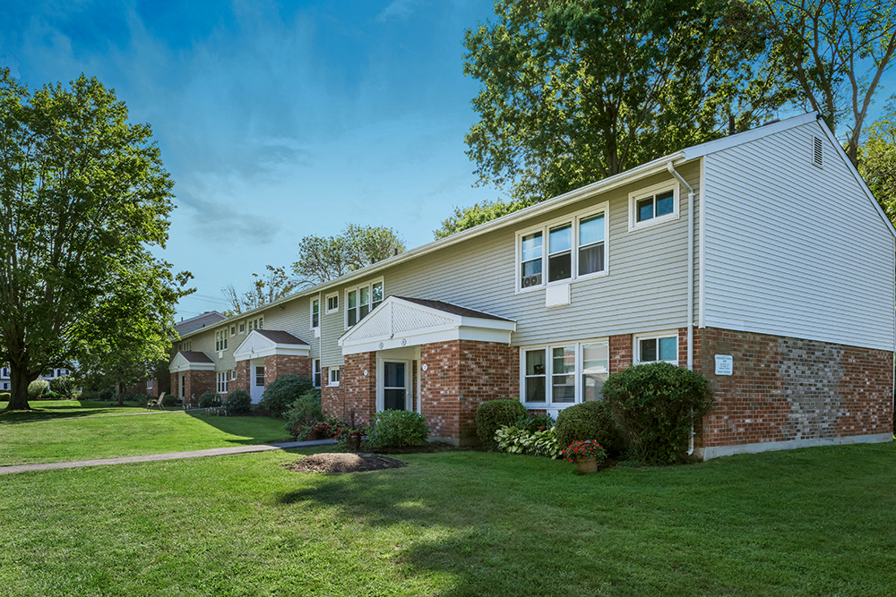 a row of houses with a lawn and trees