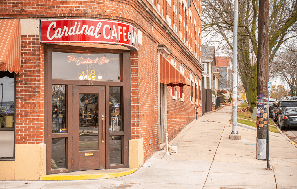 The front of a building with a red sign that says Cardinal Cafe.