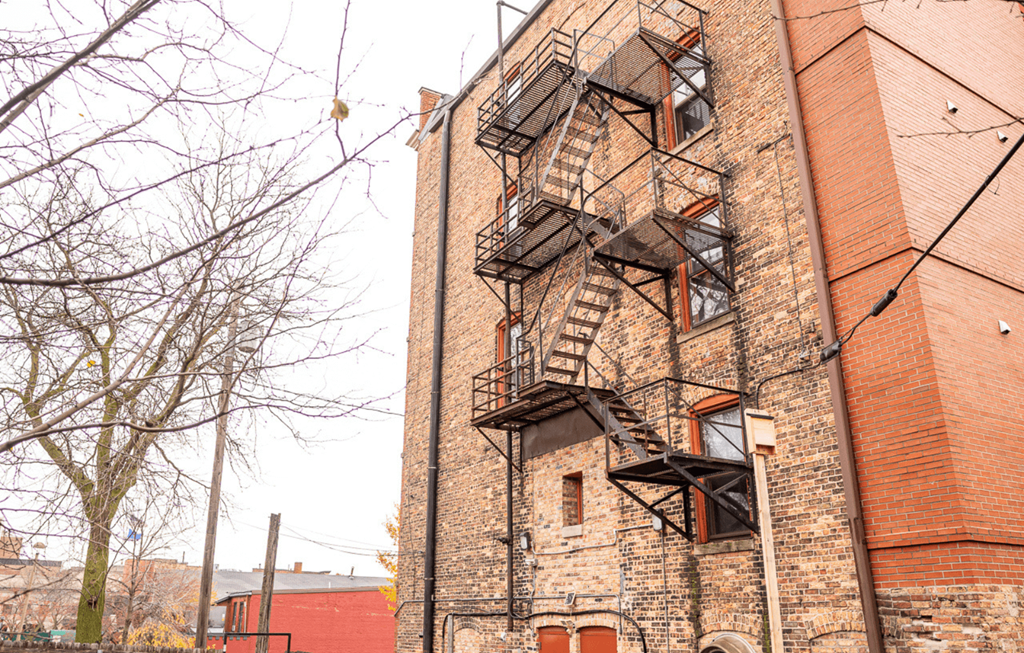 A tall brick building with a fire escape on the side.