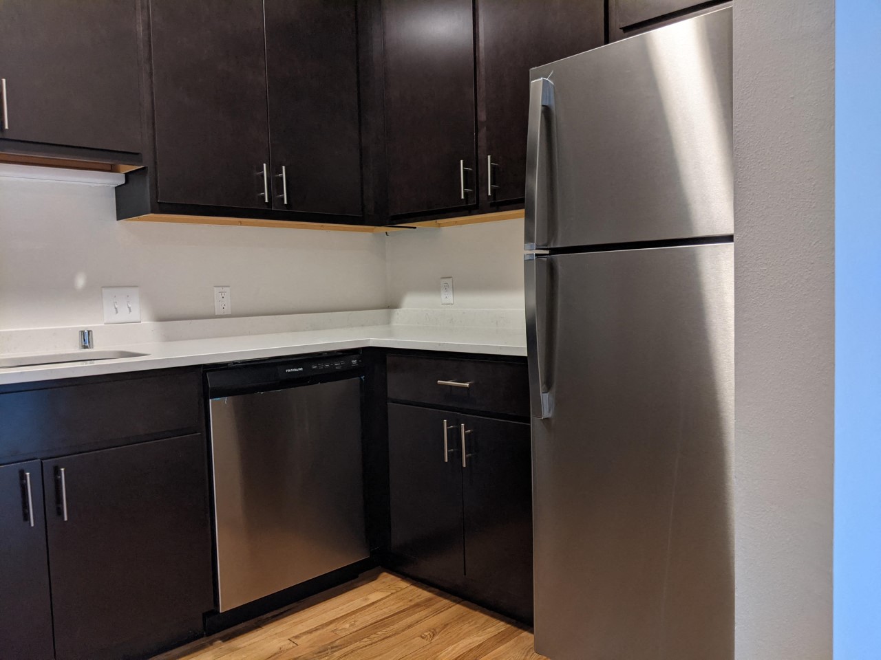a kitchen with black cabinets and a stainless steel refrigerator