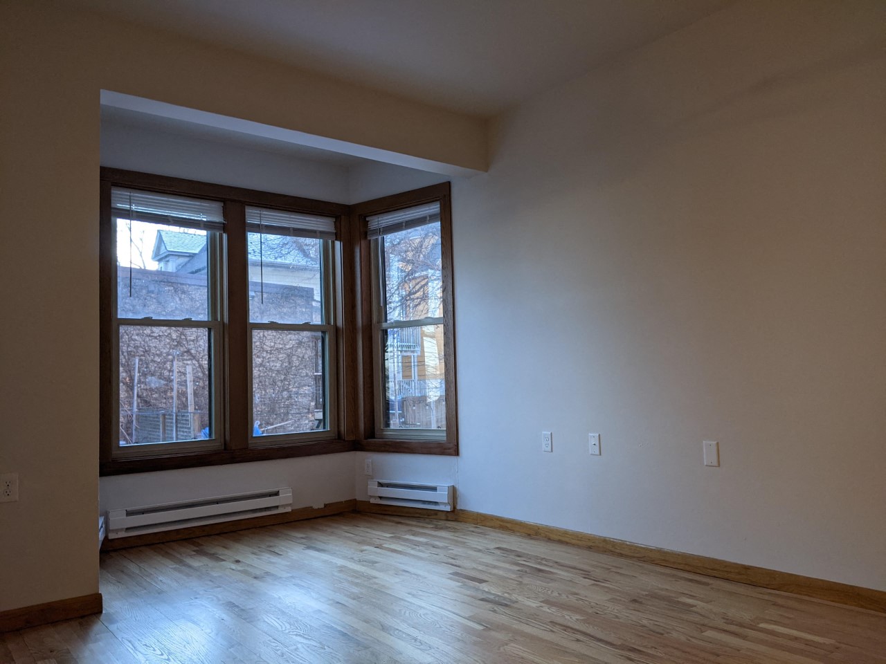 an empty living room with large windows and wooden floors