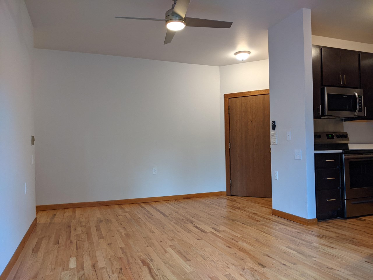 an empty living room with wood flooring and a ceiling fan