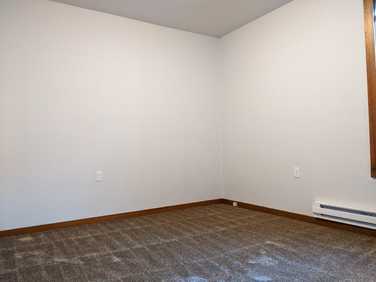 an empty room with a carpet and white walls