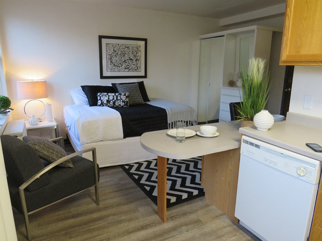 a kitchen and living room with a bed in the background