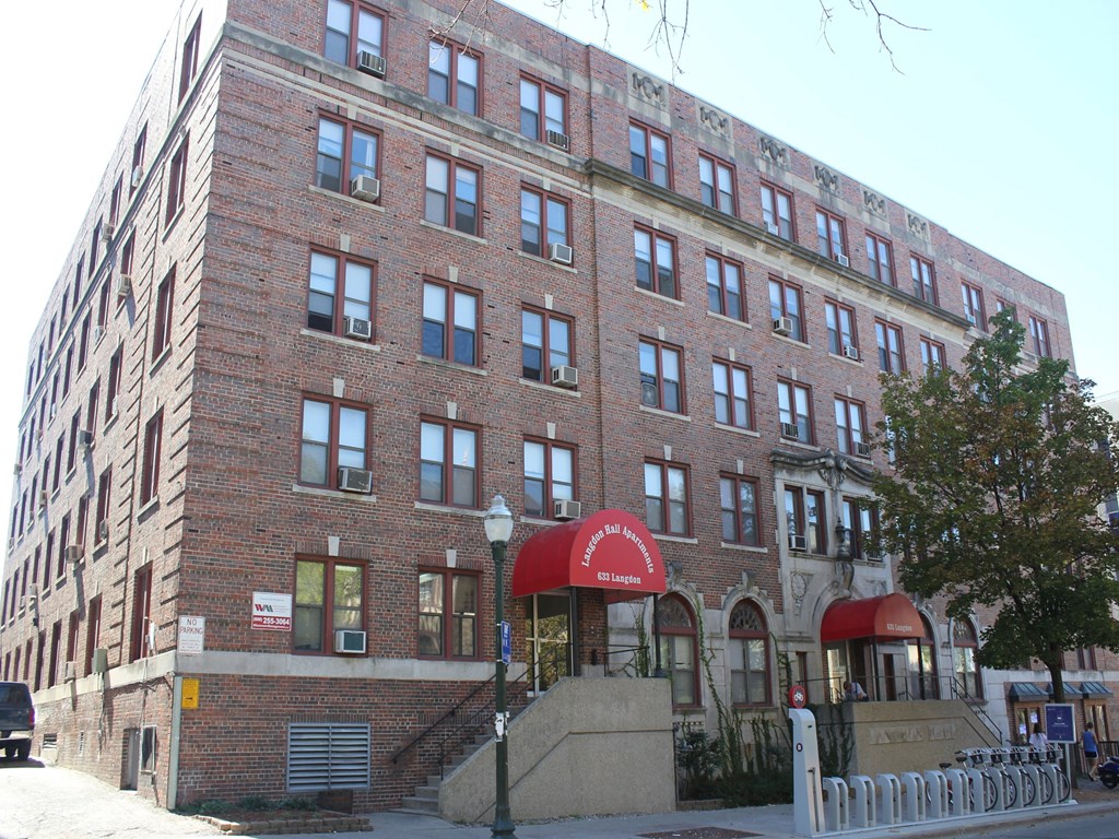 a brick building with a red awning in front of a street