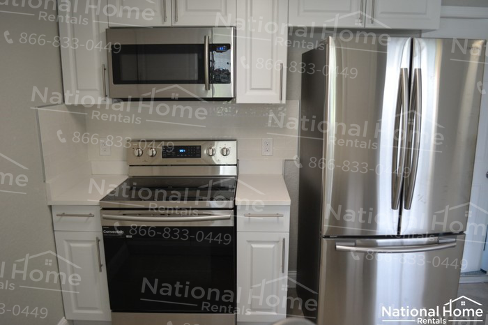 A kitchen with a refrigerator, oven, and microwave.
