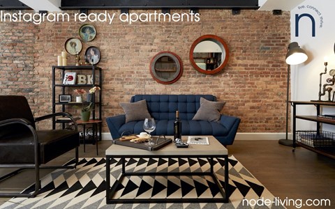 A living room with a brick wall and a black and white rug.