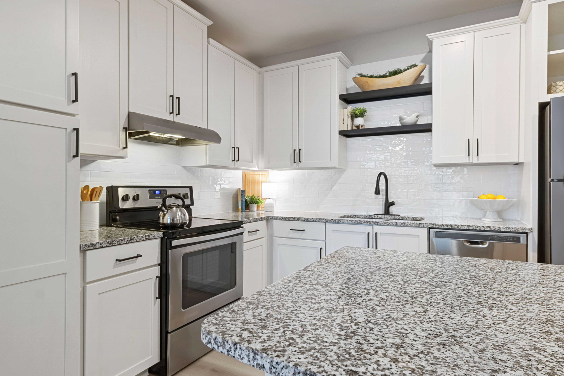 A kitchen with white cabinets and a black stove top oven.
