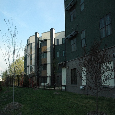 A building with a green fence and a tree in front of it.