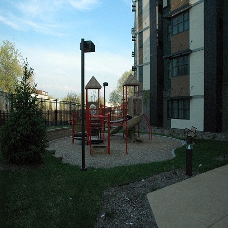 A playground with a red slide and a brown swing set.