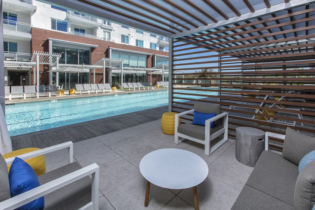 a patio with chairs and a table next to a pool