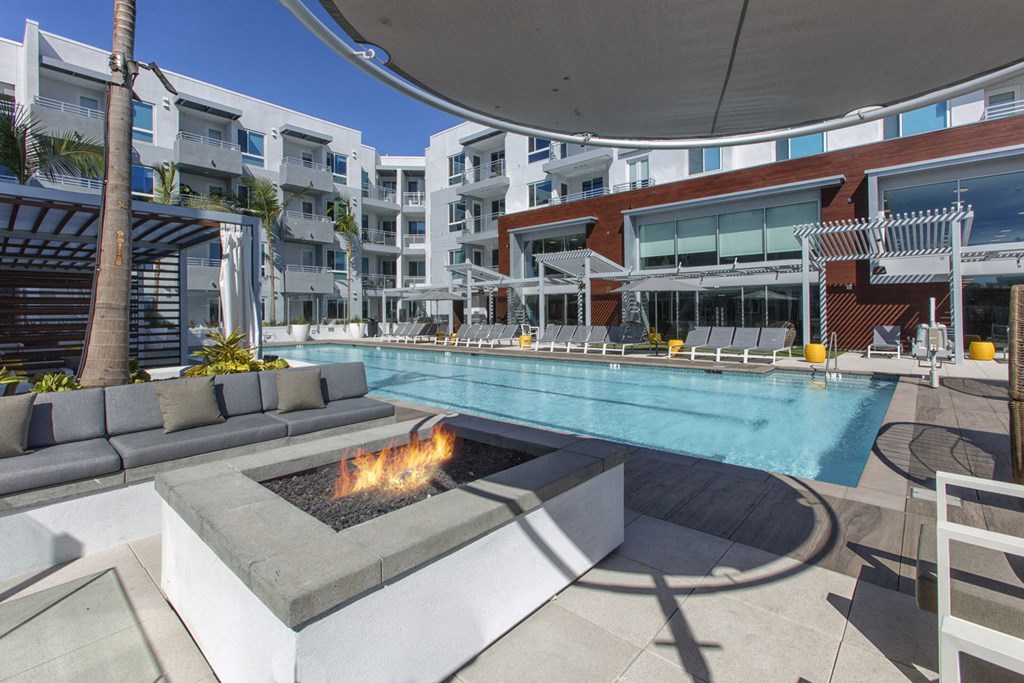 a swimming pool with a fire pit in front of an apartment building