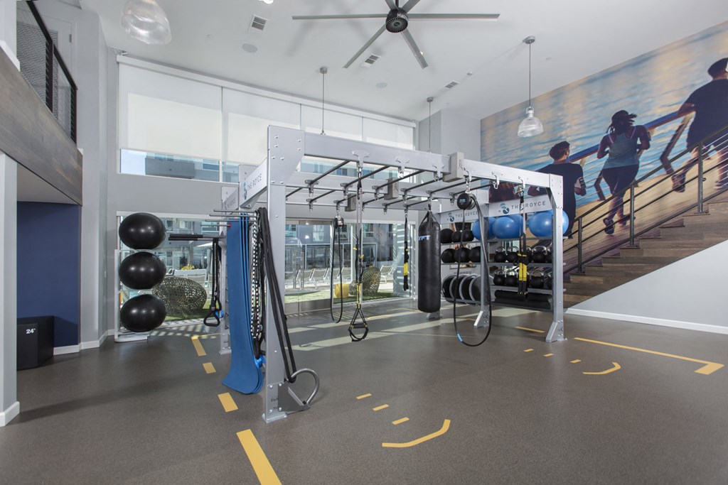 a gym with weights and cardio equipment and a staircase