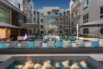 a lounge area with couches and pillows in front of an apartment building
