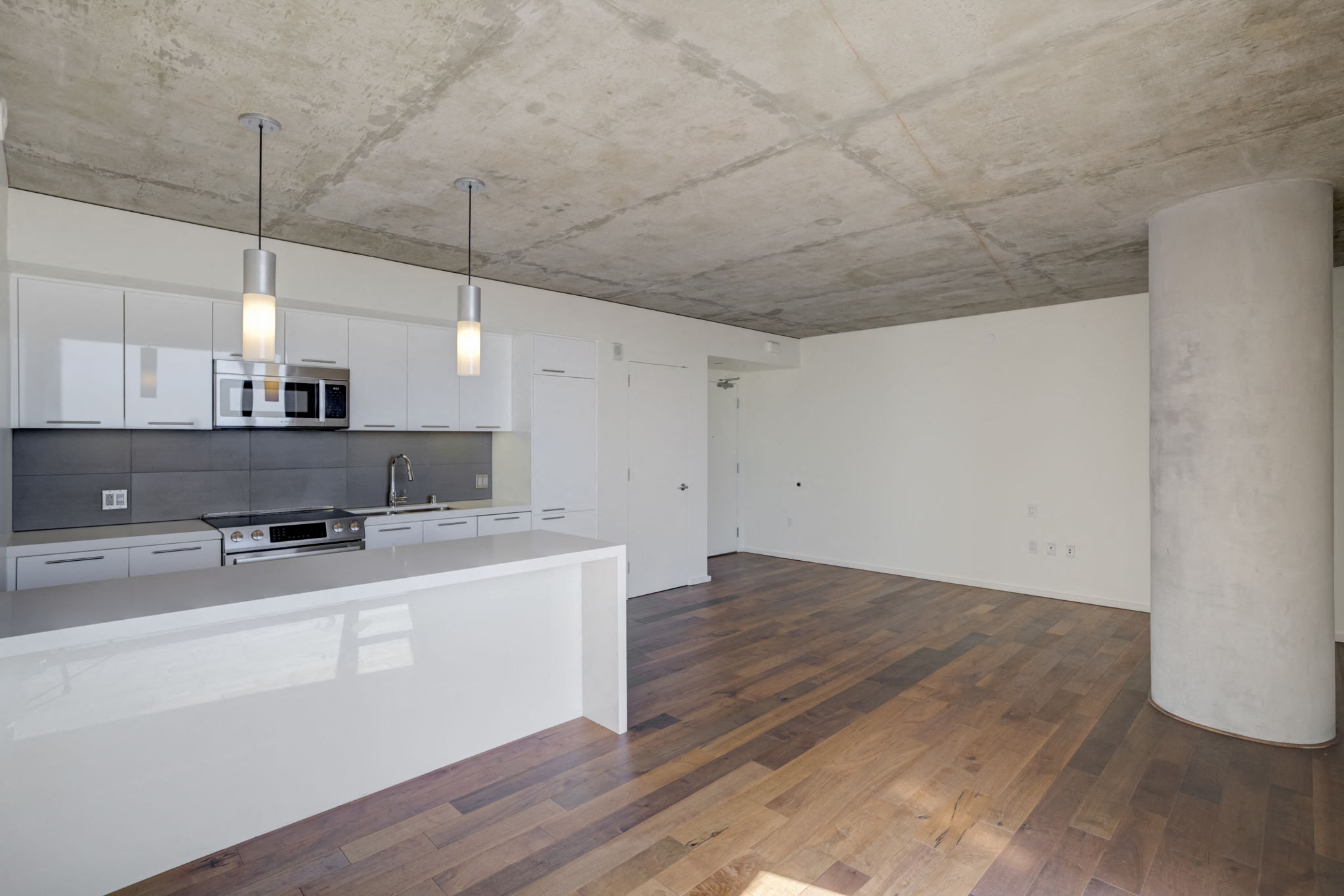a kitchen and living room with white walls and wood floors