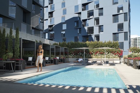 a woman standing next to a swimming pool in an apartment building