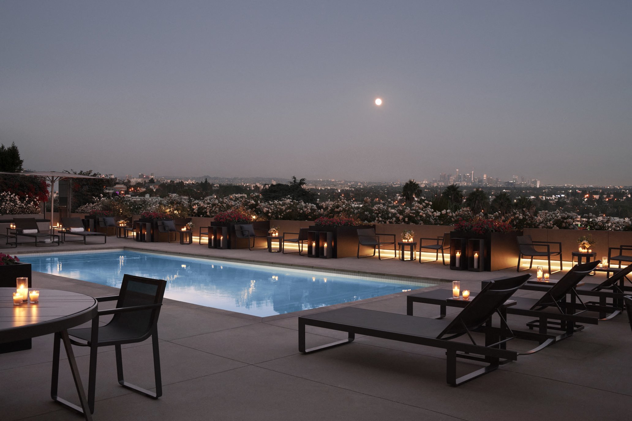 a pool at night with a view of the city and a full moon