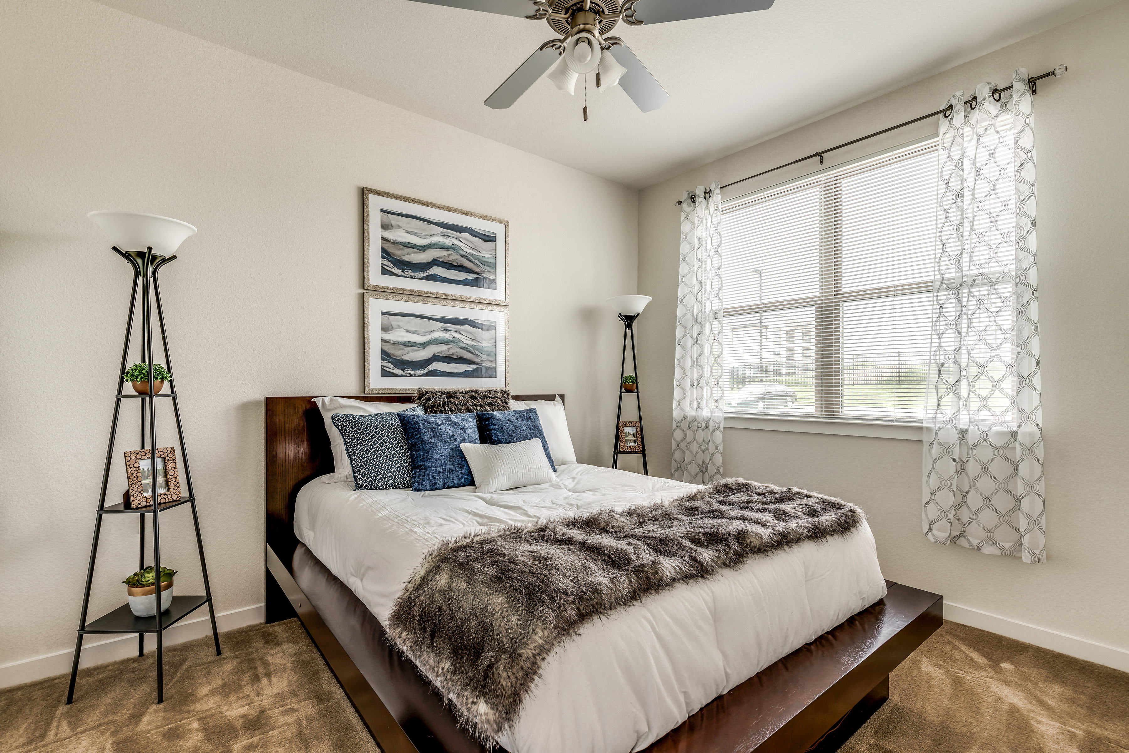 Bright bedroom featuring a comfortable bed, wood-style flooring, and large windows that fill the space with natural light.