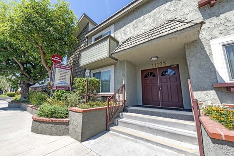 the front of a house with stairs and a sign in front of it