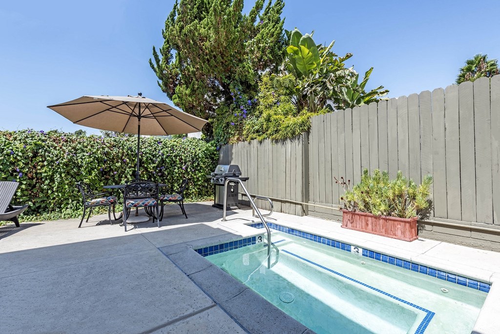 a backyard with a pool and a fence and a table and umbrella